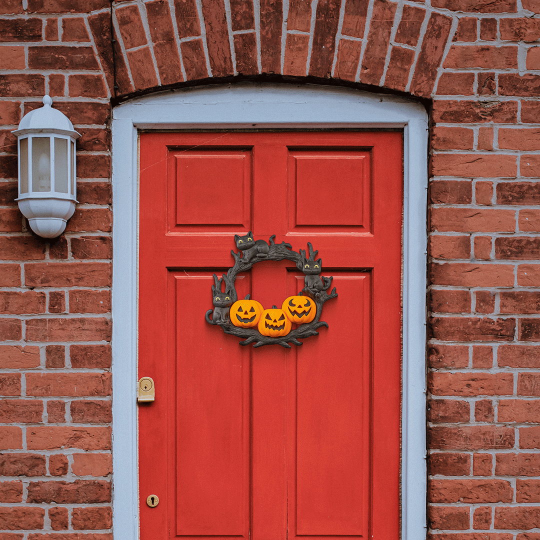Red door with Halloween wreath on a brick wall