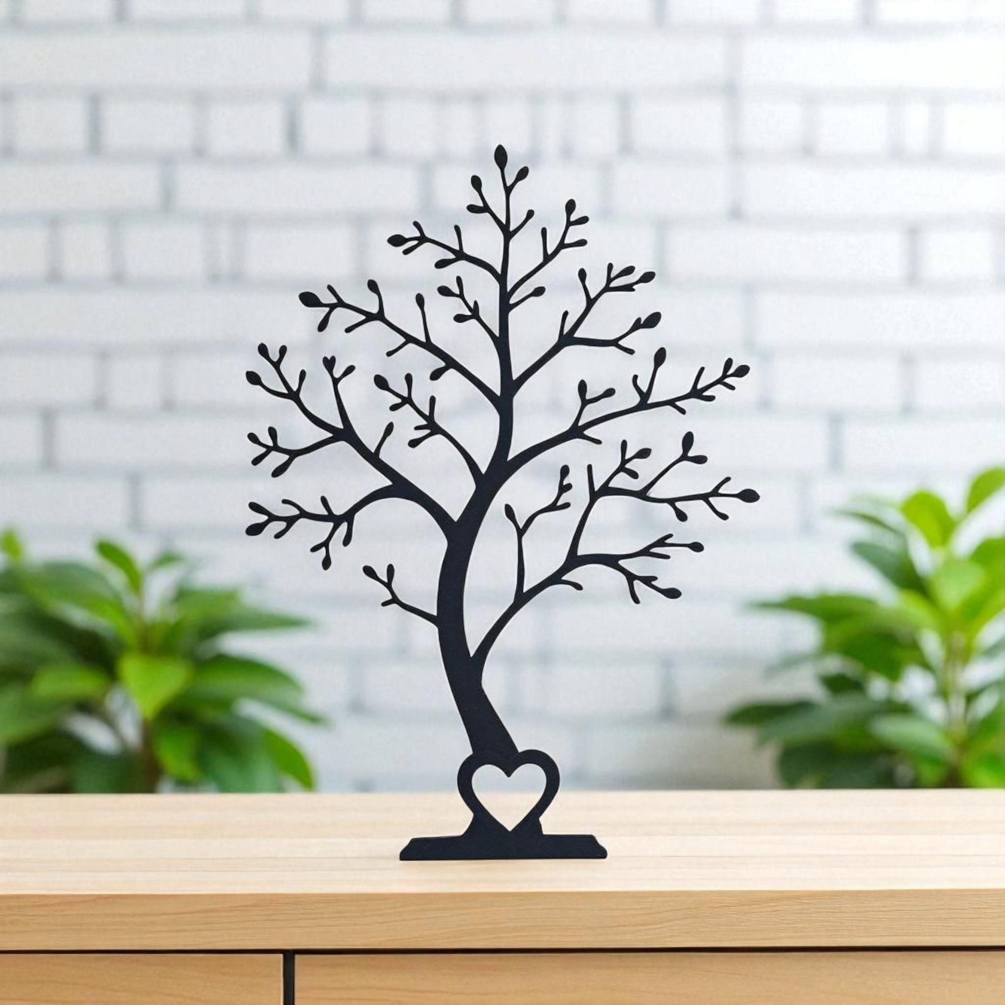 Black tree sculpture with a heart at the base on a wooden surface with a blurred background
