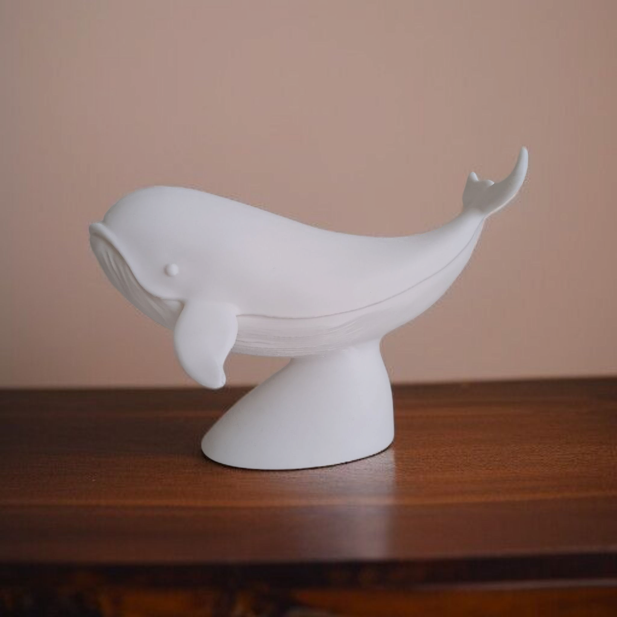White whale-shaped object on a wooden surface with a beige background