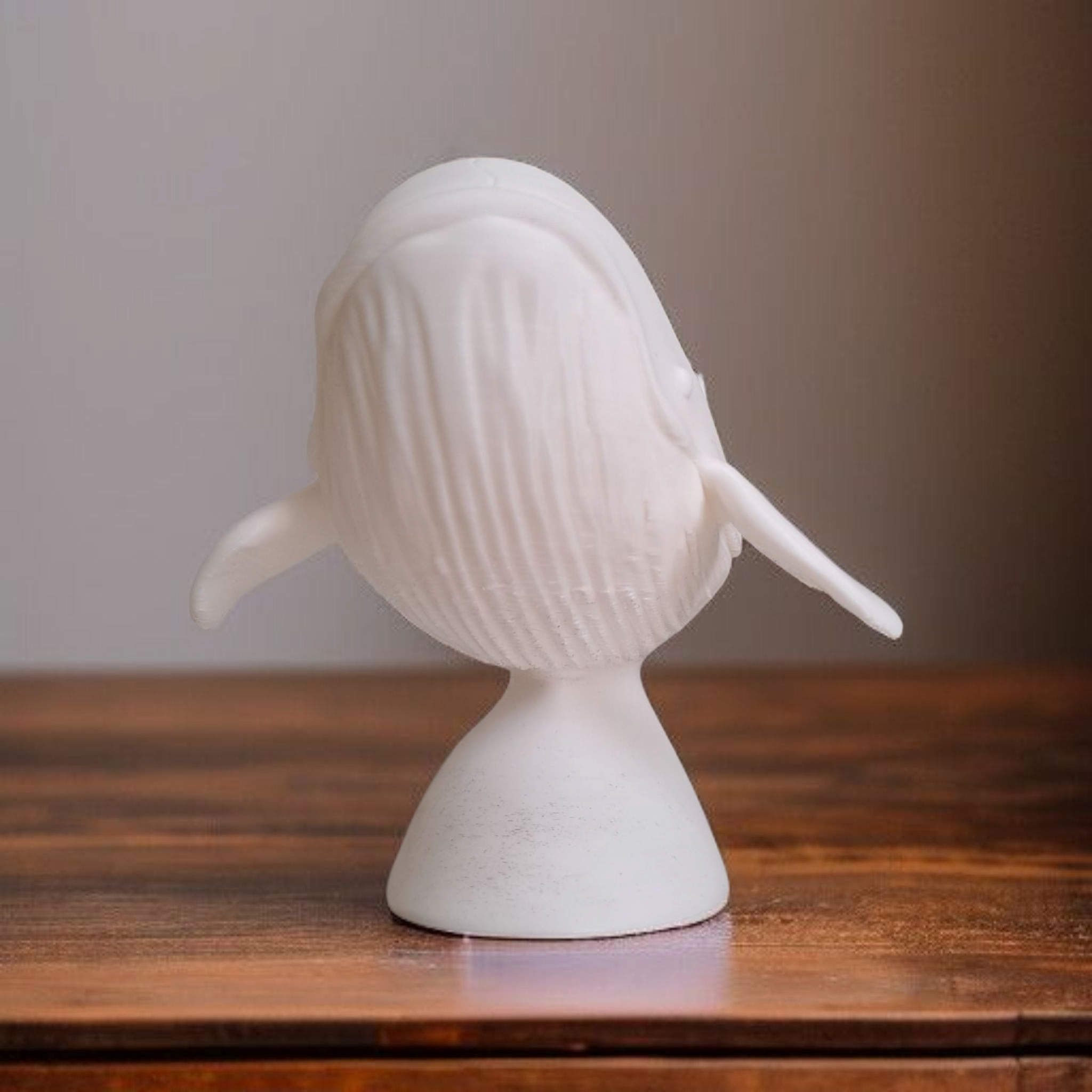 White whale sculpture on a wooden surface with a neutral background