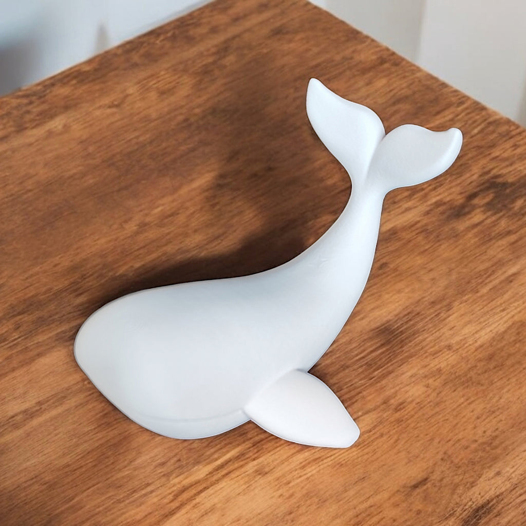 White ceramic whale figurine on a wooden surface