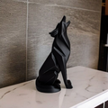 Black wolf statue on a marble surface with a stone wall background