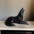 Black wolf sculpture on a textured surface with a neutral background