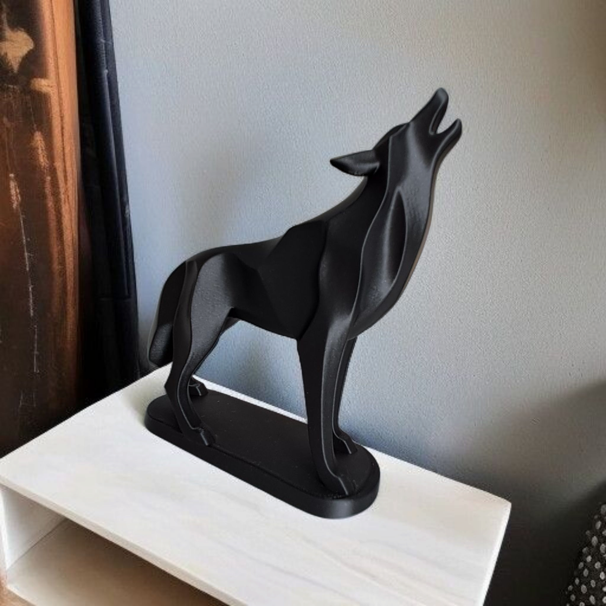Black wolf sculpture on a white surface with a neutral background