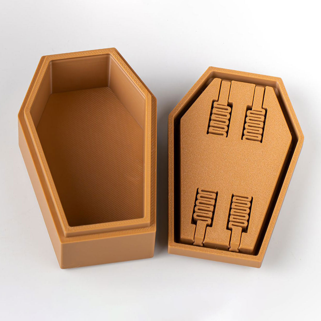 Brown coffin-shaped box with a lid featuring embossed designs on a white background