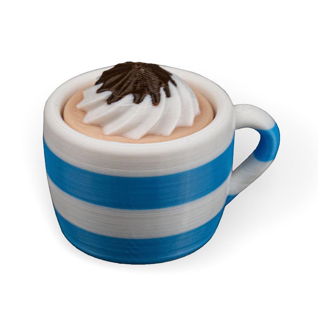 White mug with blue stripe filled with a chocolate drink and whipped cream on a white background