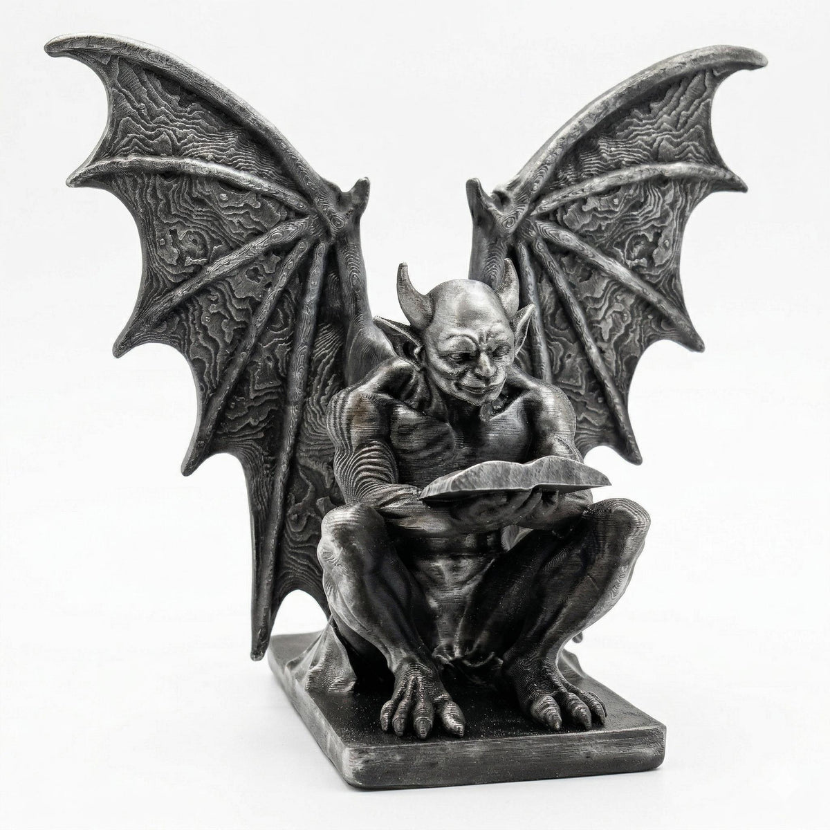 Gargoyle bookend in hand-painted silver: a winged gargoyle crouched over an open book