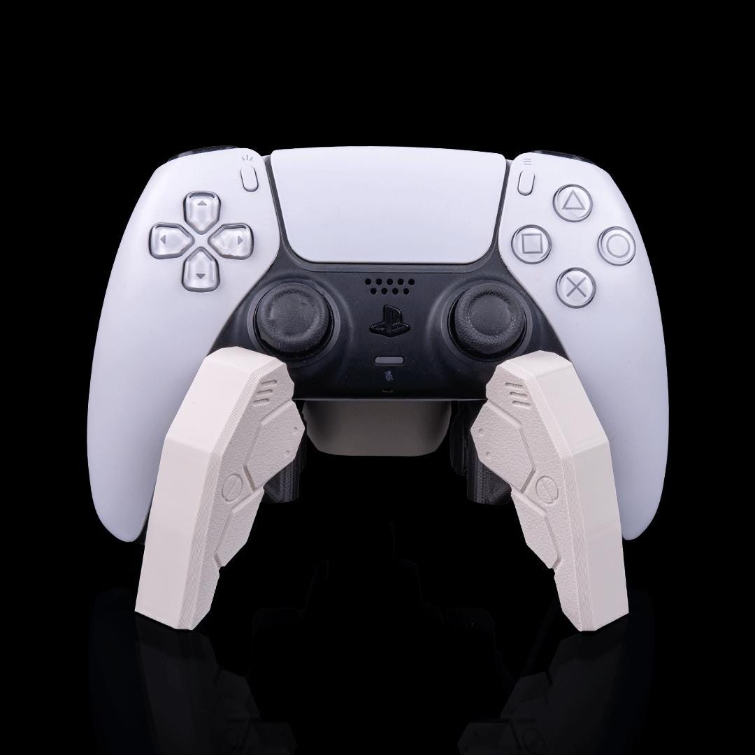 Robot spider stand holding a white PS5 controller from the front