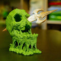 Green and beige fantasy creature figurine on a dark surface