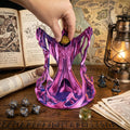 A hand dropping a die into the wizard dice tower on a table with a map, lantern and dice