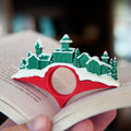 Christmas-themed bookmark with a snowy village design on an open book.