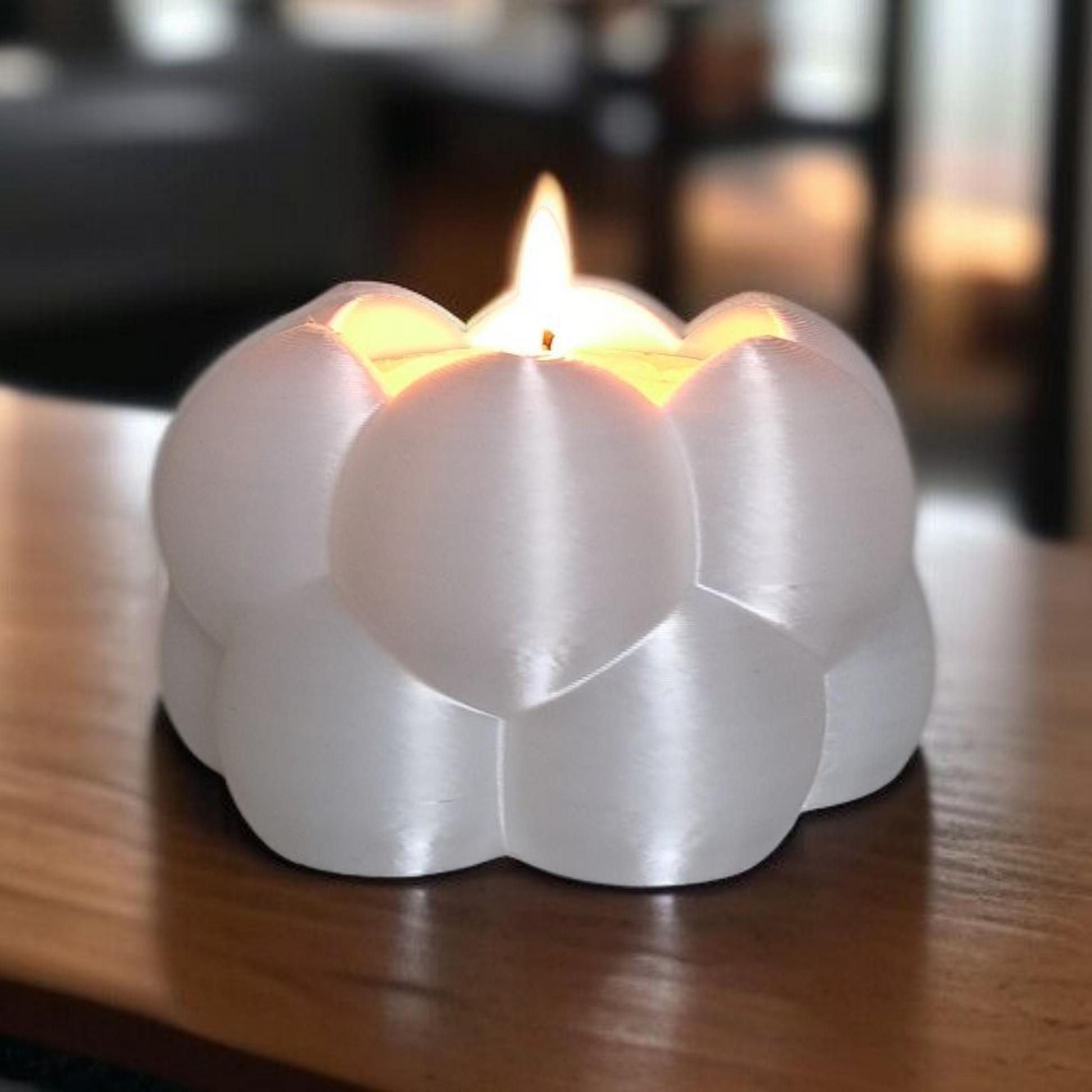 White stone candle holder with a lit candle on a wooden surface