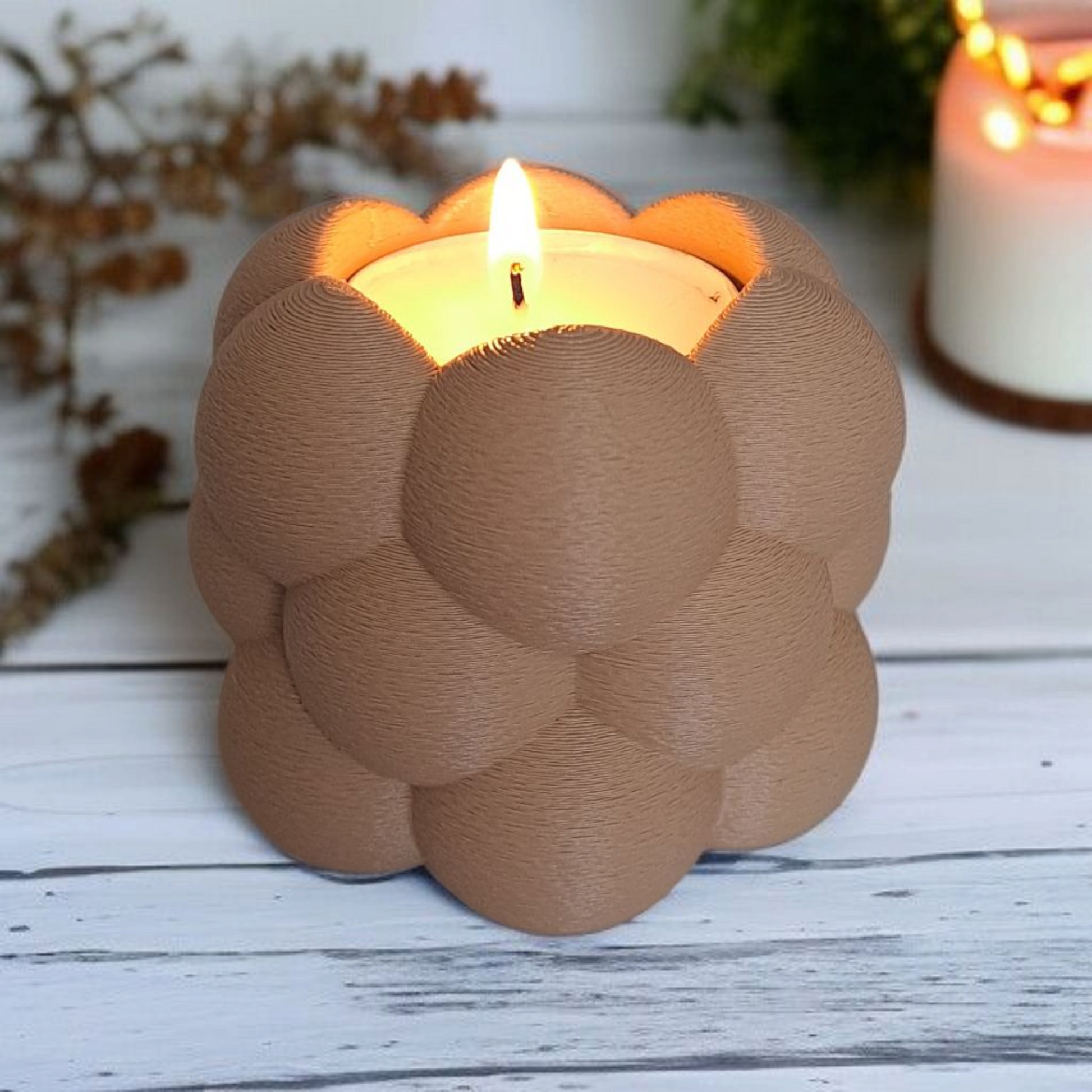 Candle in a decorative brown holder on a wooden surface with blurred background