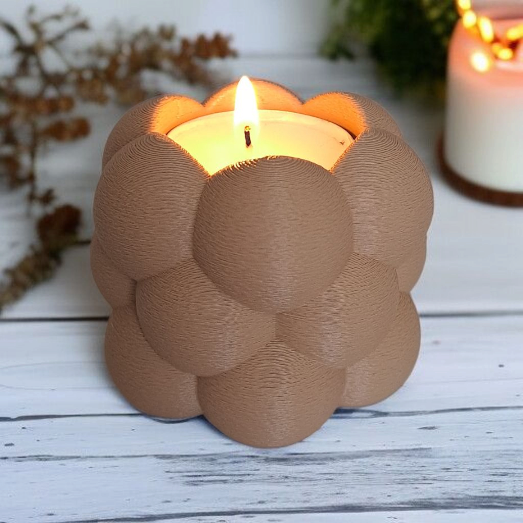 Candle in a decorative brown holder on a wooden surface with blurred background