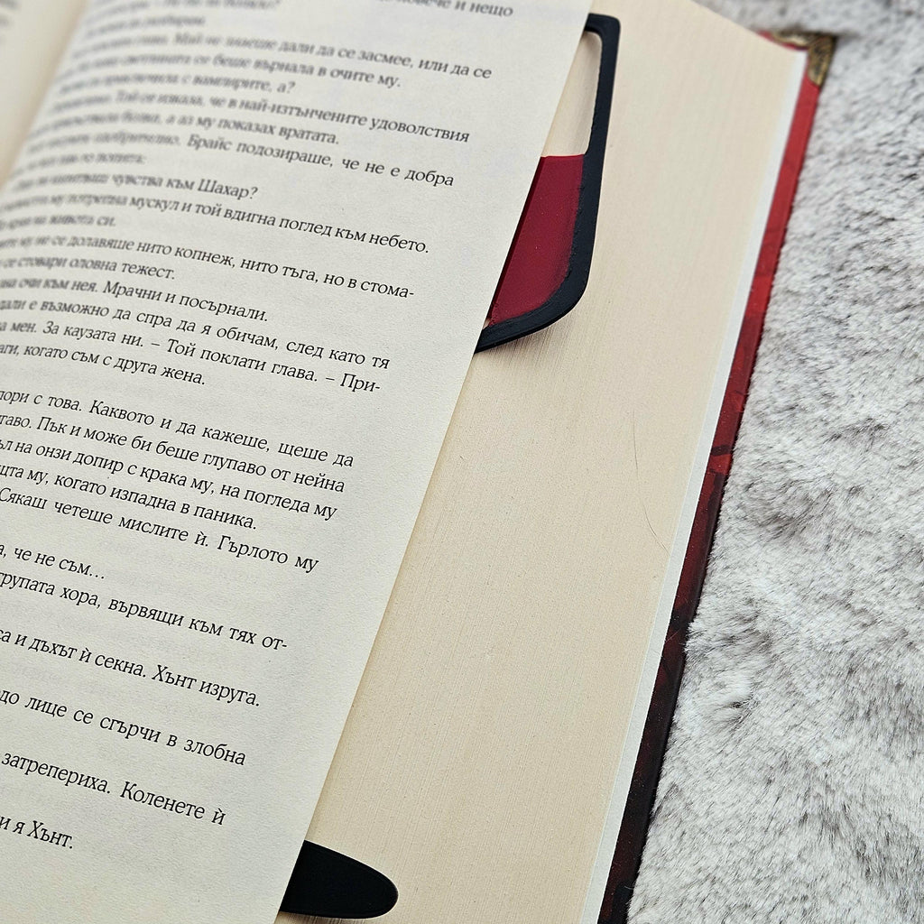 Wine glass bookmark tucked in a book, the red wine showing at the top