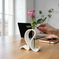 White S-curve test tube vase holding a pink rose on a desk