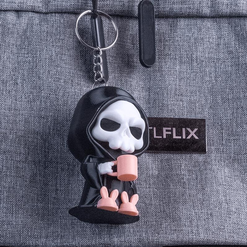 Small Coffin Break grim reaper keyring clipped to a grey bag