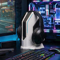 White and black sci-fi headset stand holding black headphones beside a gaming PC