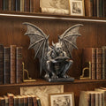 Gothic gargoyle bookend in silver holding up old books on a wooden library shelf