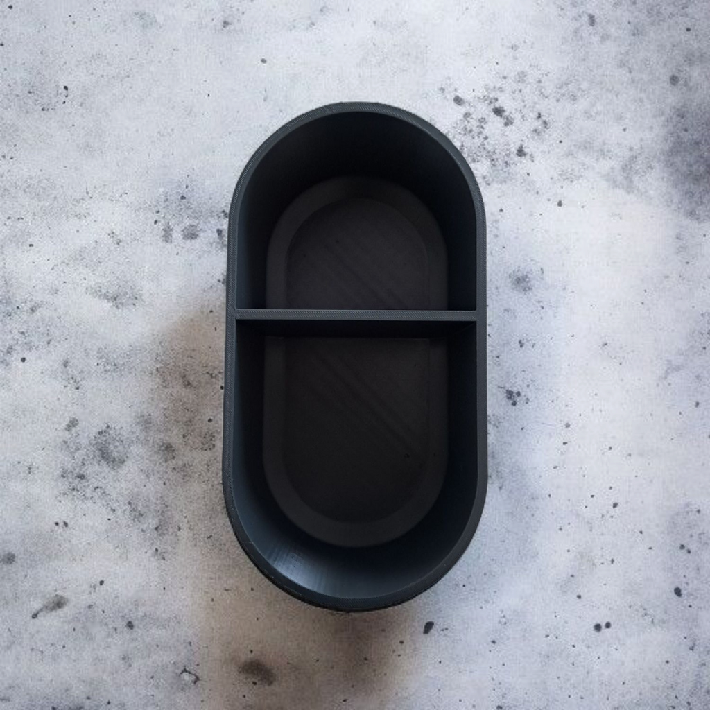 Black oval container on a textured gray surface