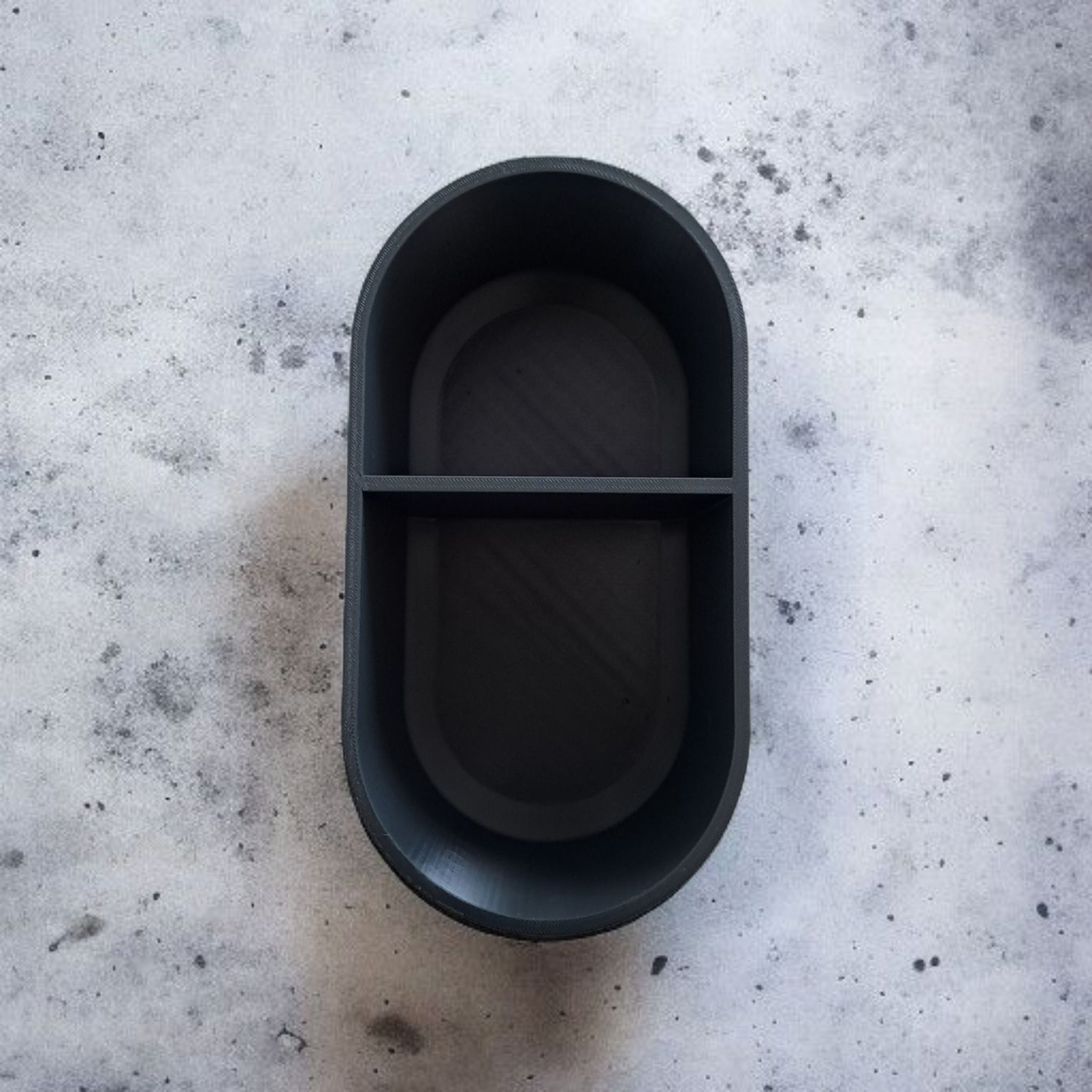 Black oval container on a textured gray surface