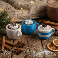 Three small mugs with hot chocolate, whipped cream, and cookies on a wooden surface with cinnamon sticks and oranges.