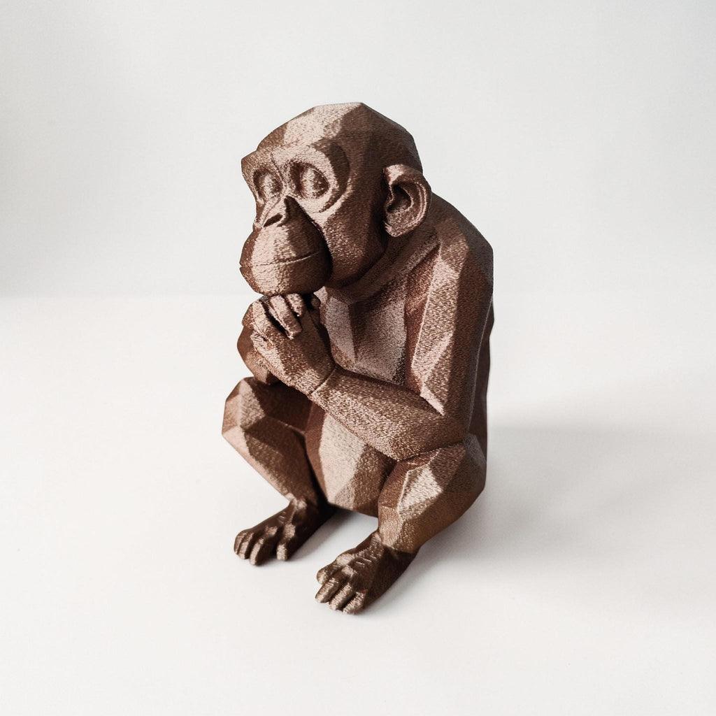 Brown monkey figurine holding a banana on a white background