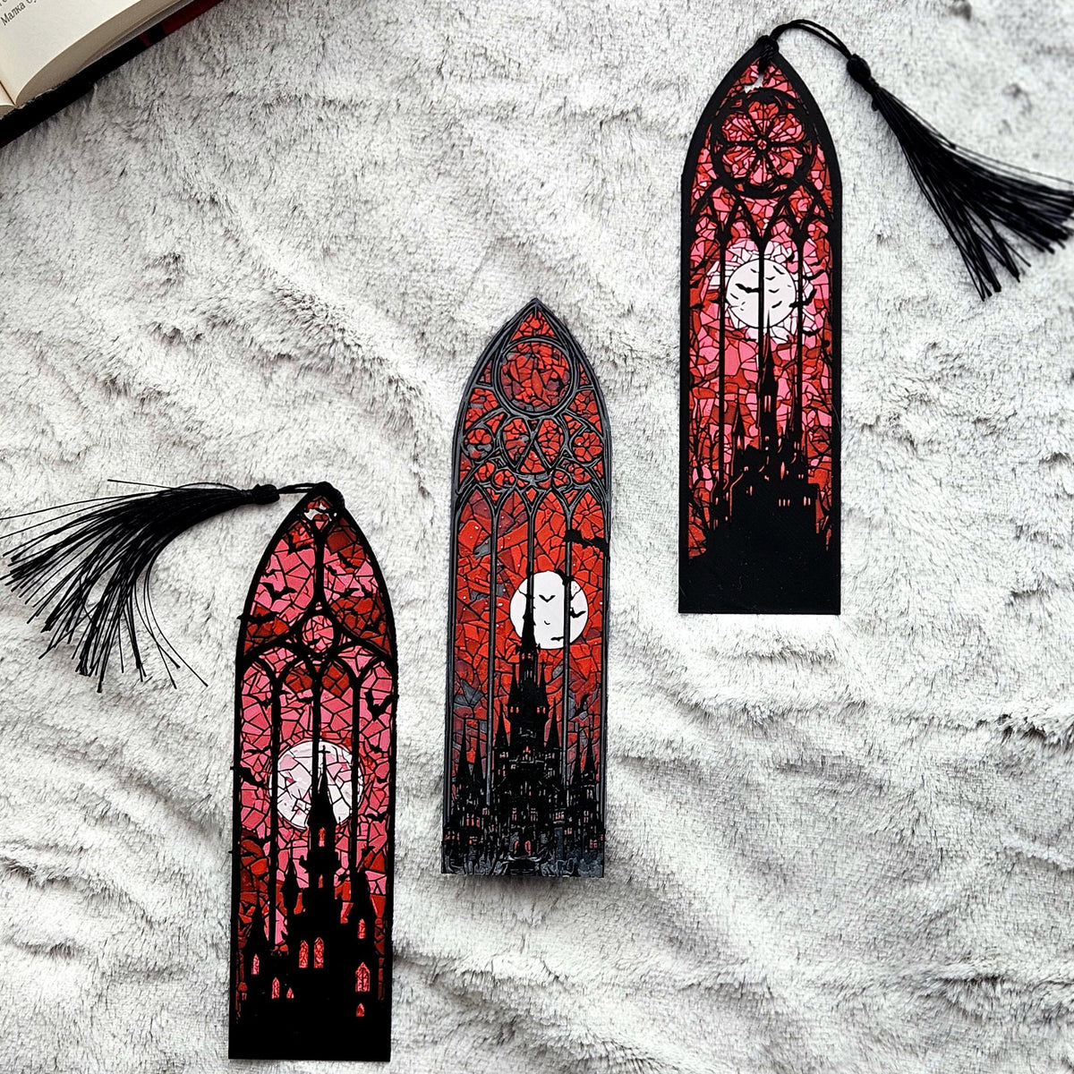 The three gothic stained glass bookmarks laid out on a blanket