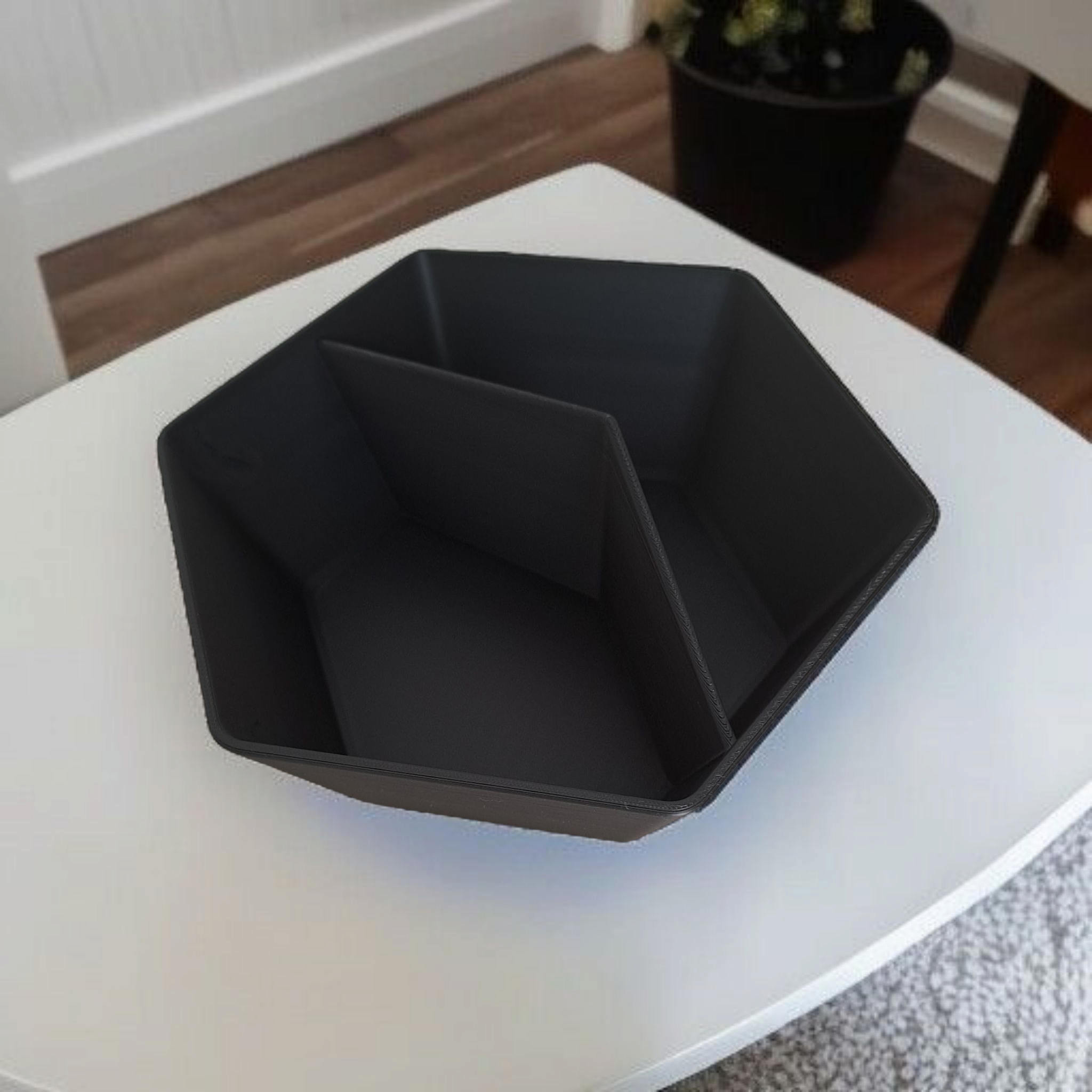 Black geometric bowl on a white surface with a blurred background