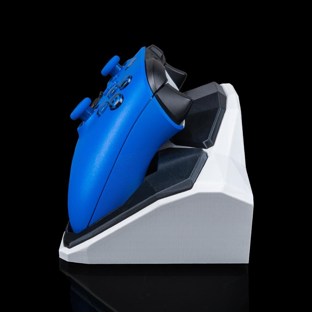 White and black geometric controller stand from the side, holding a blue Xbox controller