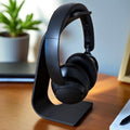 Black headphones on a stand with a blurred indoor background