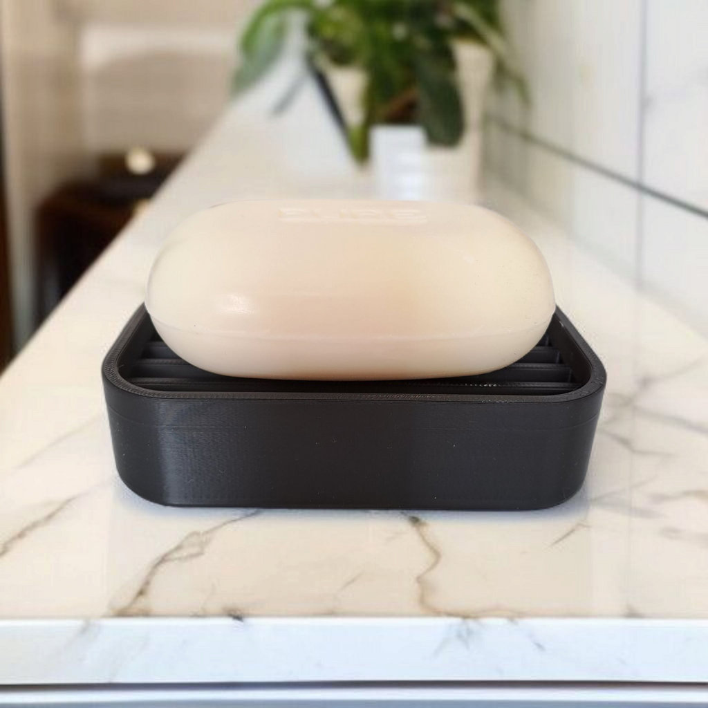 Bar of soap in a black soap dish on a marble countertop