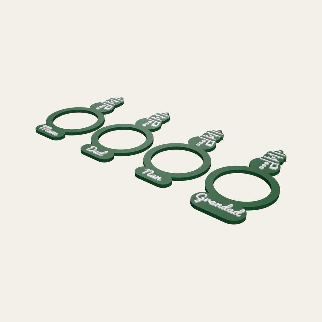 Four green napkin rings with snowman toppers, each with a family name such as Mum or Grandad